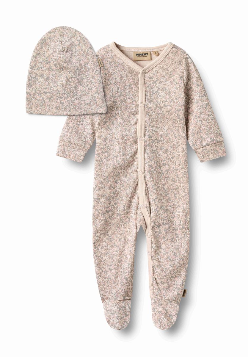 A baby footed one-piece sleeper and matching beanie hat in a speckled beige and light pink fabric, displayed on a clean white background.