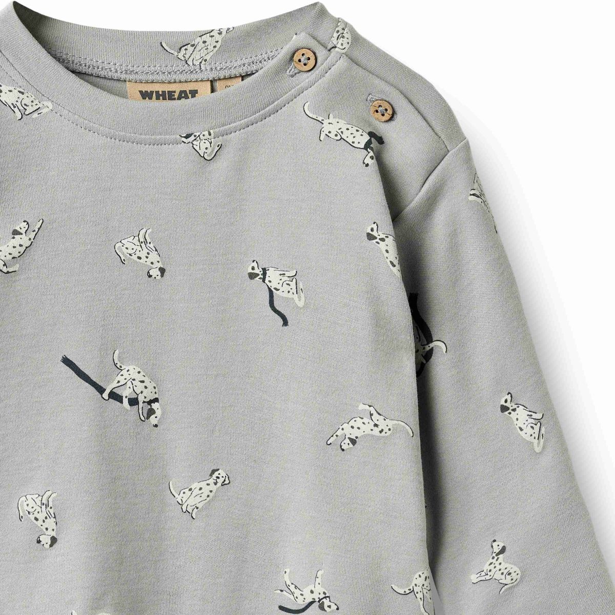 A close-up of a light gray long-sleeve children's top with an allover Dalmatian print and snap closures at the shoulder.