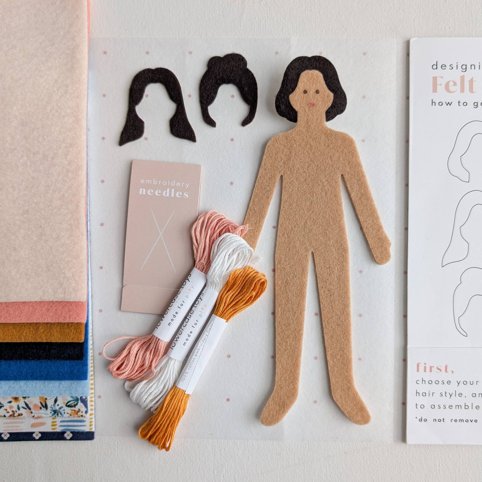 Felt doll design set with packaging, materials, and instructions on a light gray background