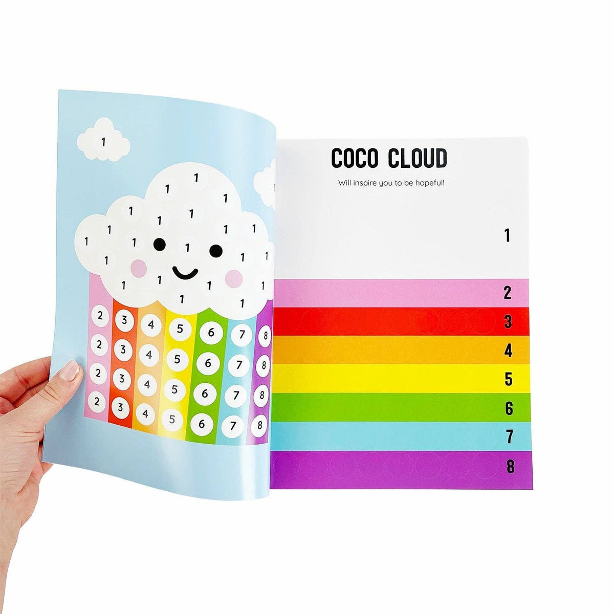 Colorful book with a cloud design and rainbow pattern, held by a hand.
