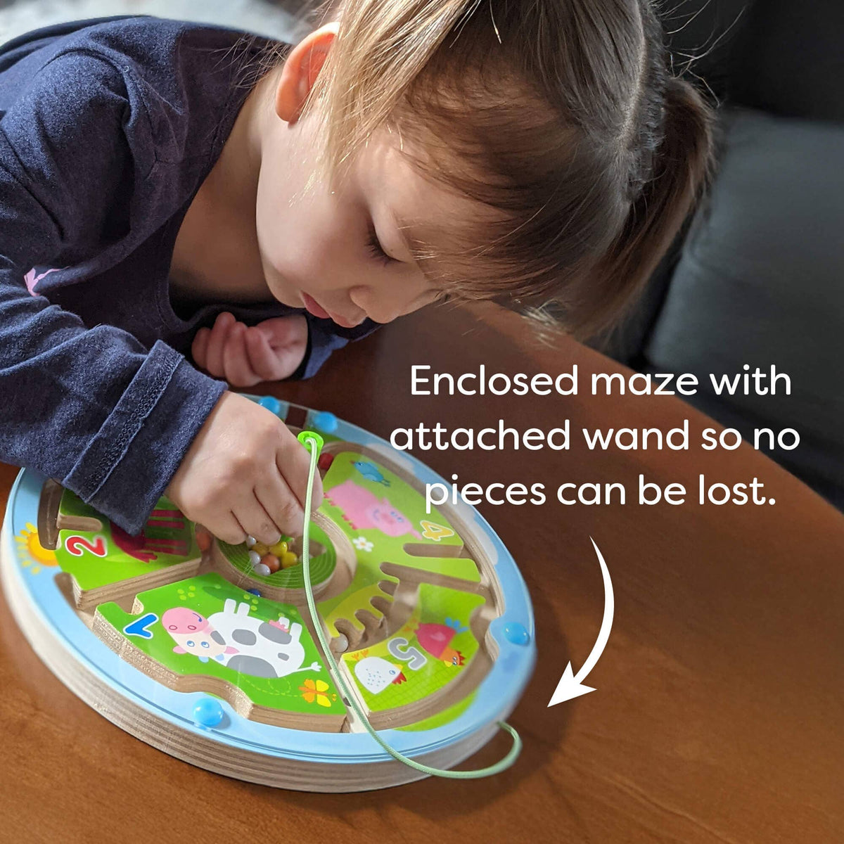 Child playing with a maze toy on a wooden table
