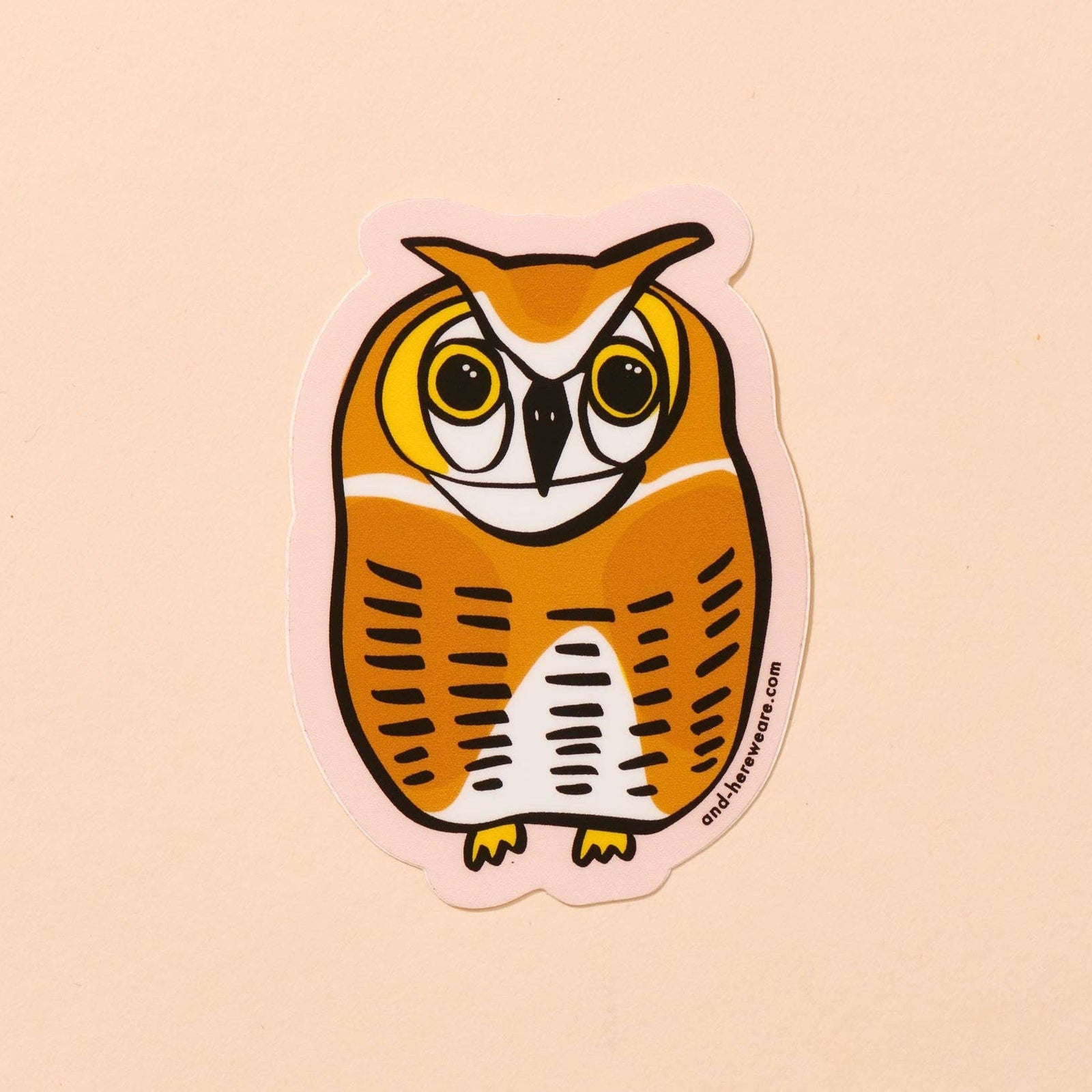 An owl-shaped sticker featuring a stylized orange and white owl with black outlines, shown on a solid pale peach background.