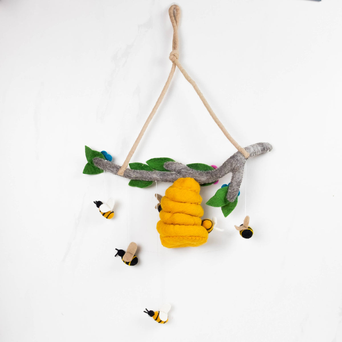 Decorative wall hanging with a bee hive, leaves, and small birds on a white background