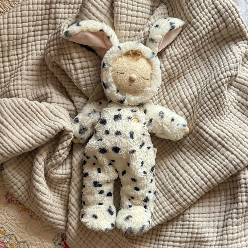 Stuffed animal toy with dog ears on a textured beige blanket