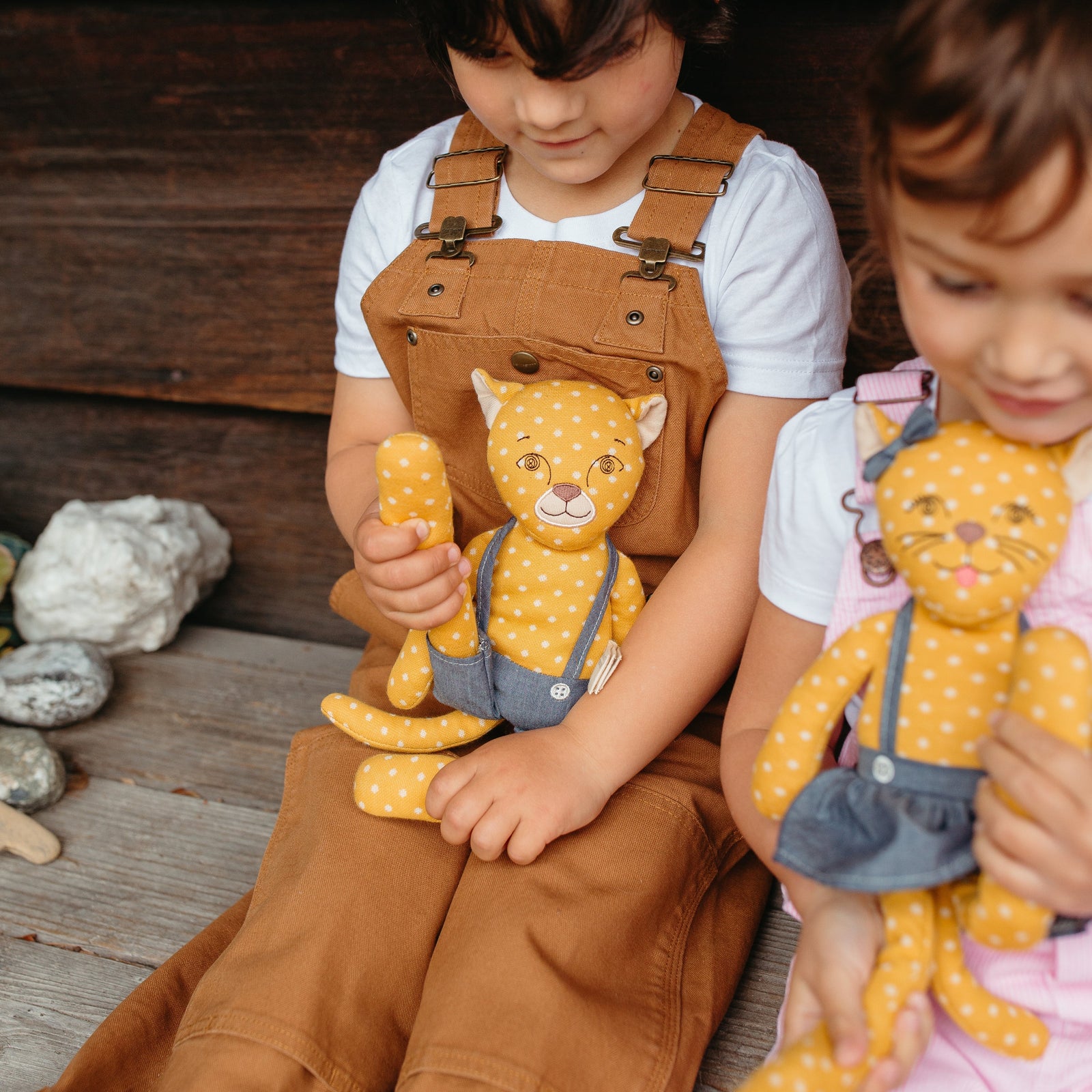 Child holding a plush toy in front of a wooden wall