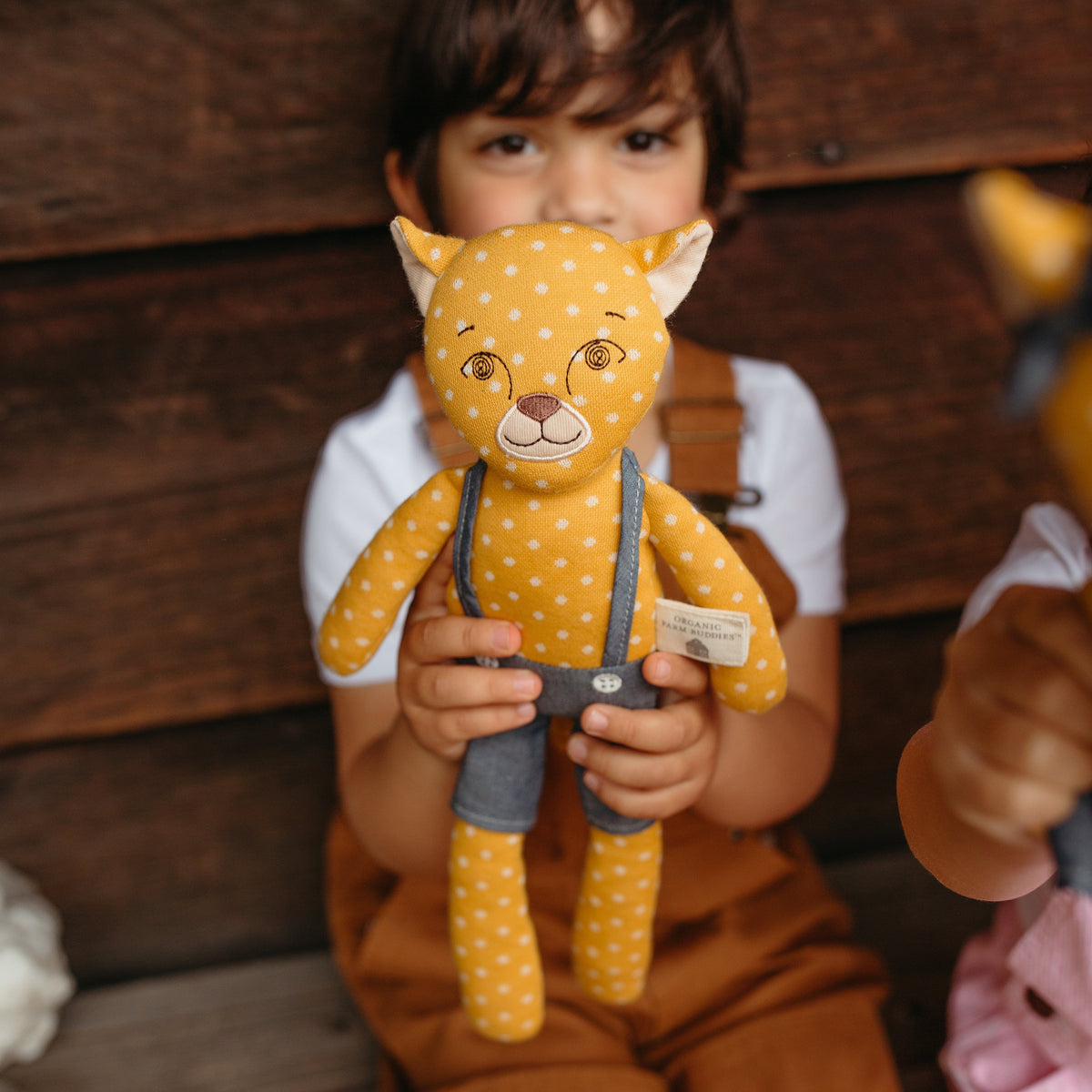 Child holding a plush toy in front of a wooden wall