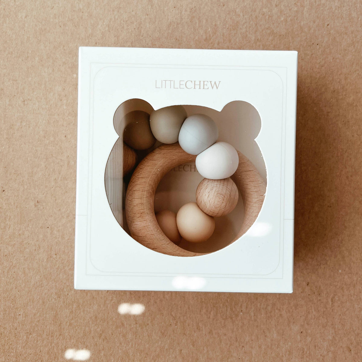 Wooden baby teething rings in a white box on a brown background