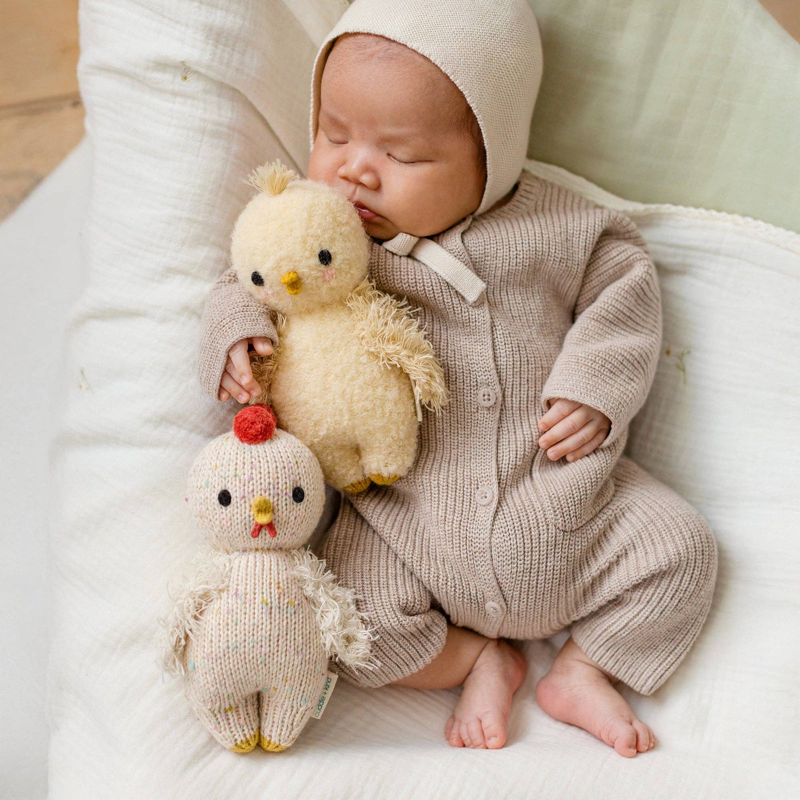 Knitted chicken toy held in a hand with a blurred floral background