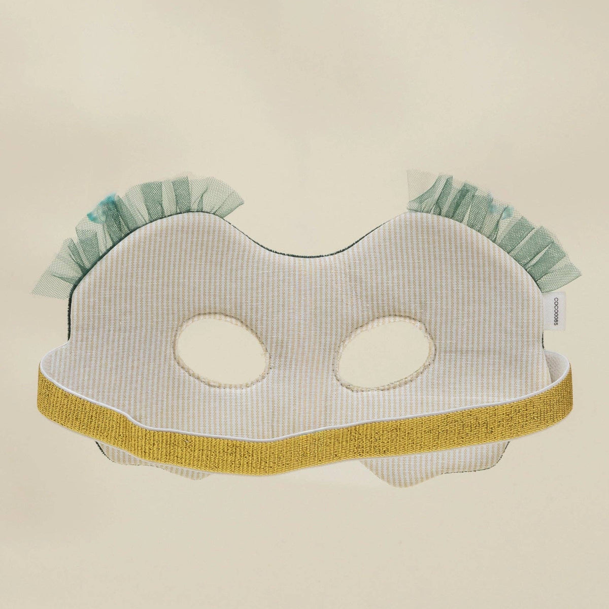 Owl mask with green ruffles on a beige background