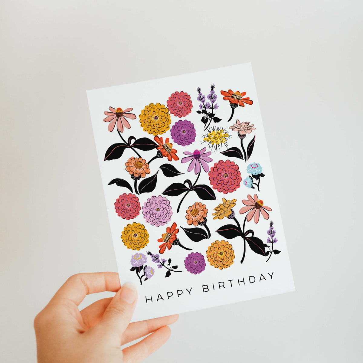 Hand holding a birthday card with floral designs and &#39;Happy Birthday&#39; text.
