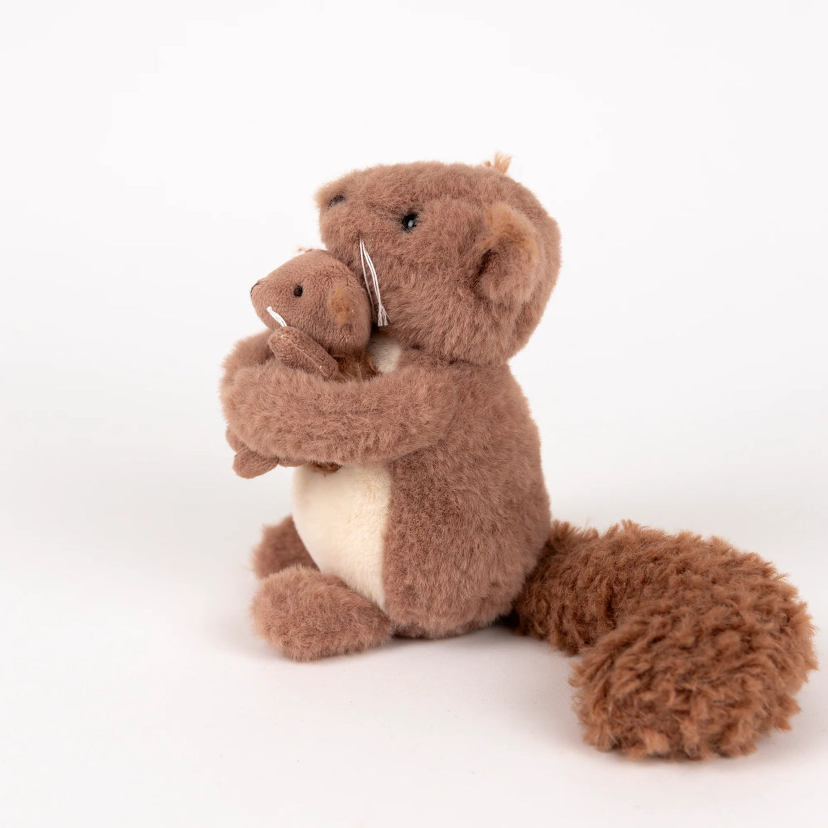 Stuffed animal squirrel holding a smaller squirrel toy on a white background