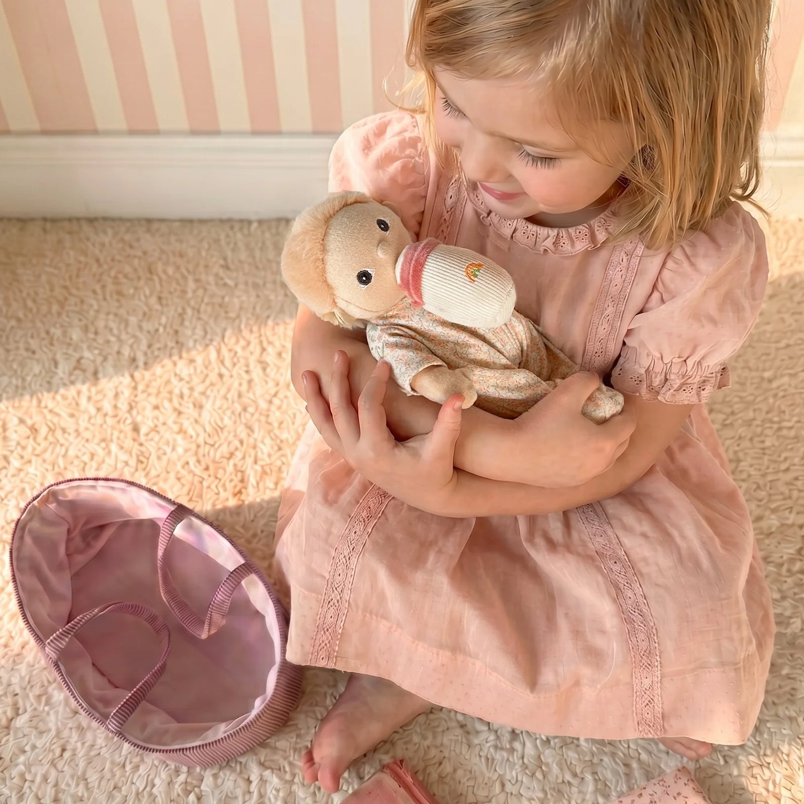 Baby doll in a pink crib with a pacifier on a white background