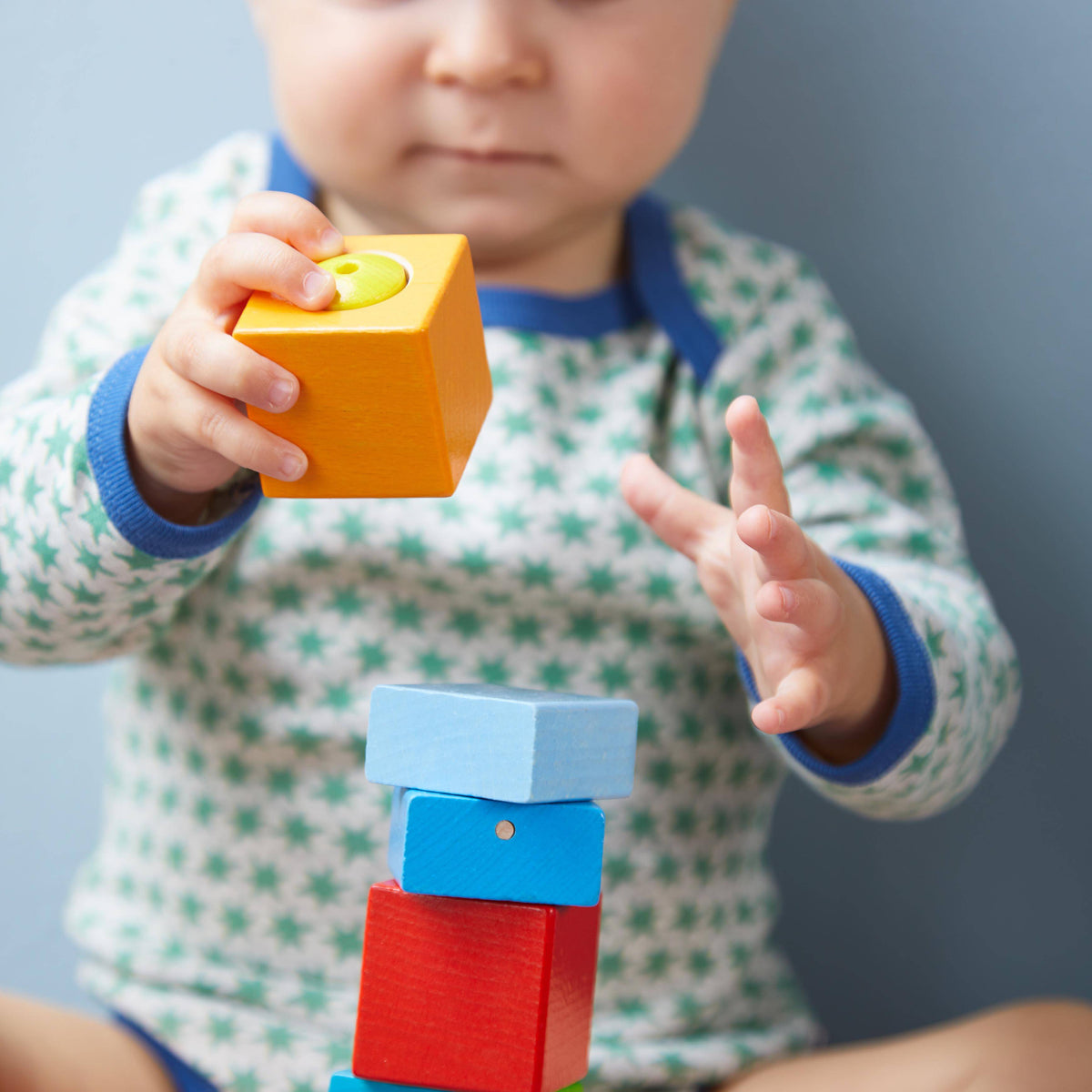 Child playing with colorful building blocks against a plain background