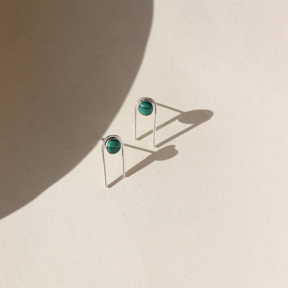 Pair of earrings with green gemstones on a beige background