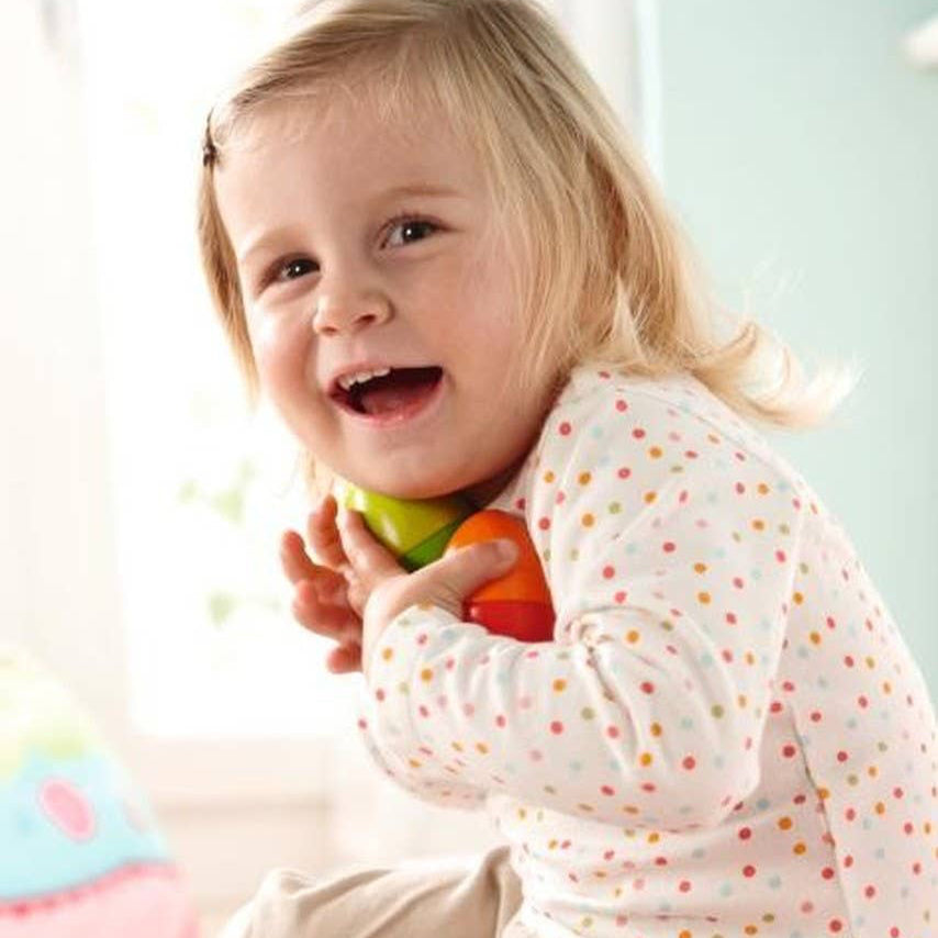 Child playing with colorful toys on a pink blanket