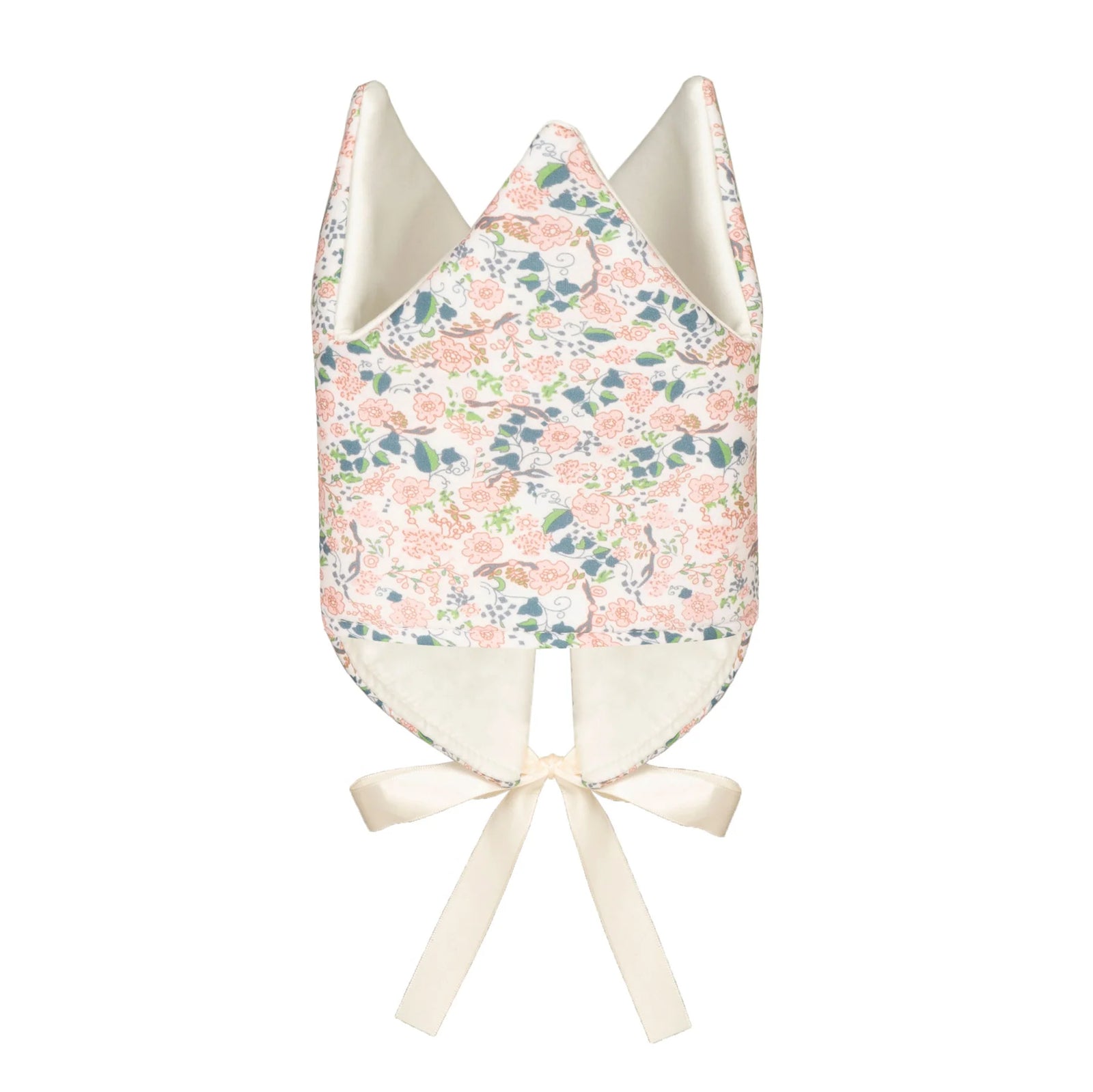 Child wearing floral fabric crown, holding a fabric wand laying on a white surface