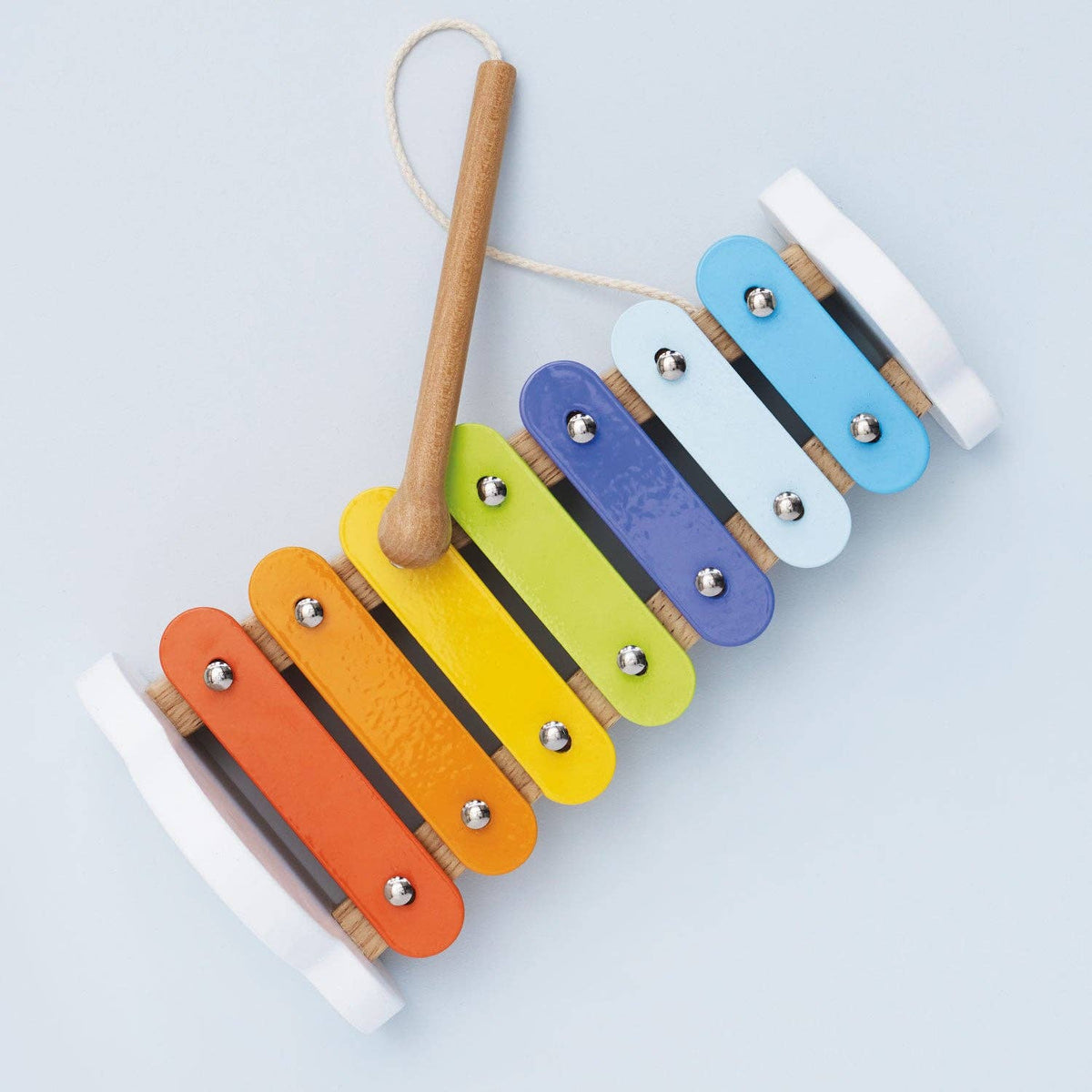 Colorful wooden xylophone with a wooden mallet on a light gray background