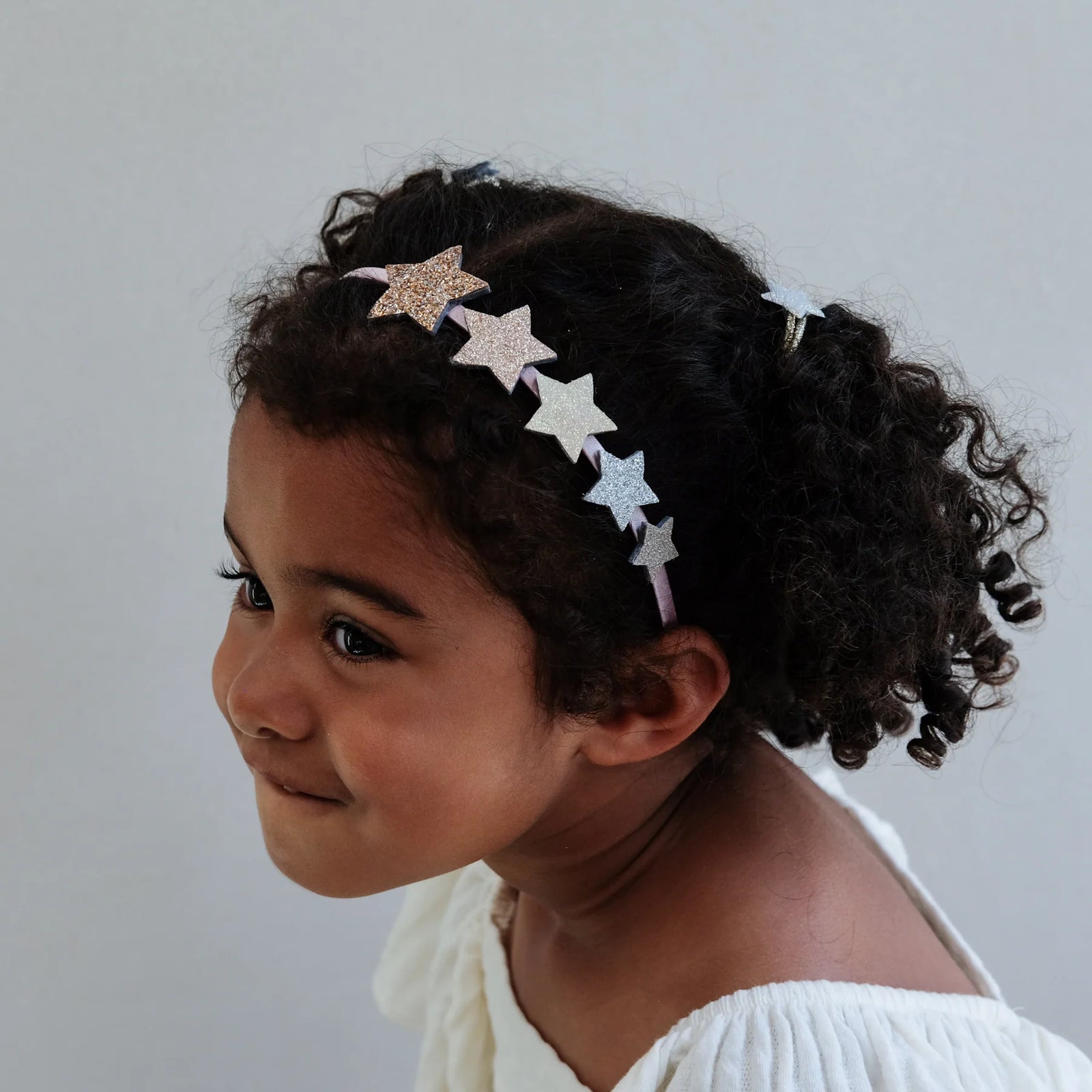 Child wearing a headband with star-shaped accessories on a plain background