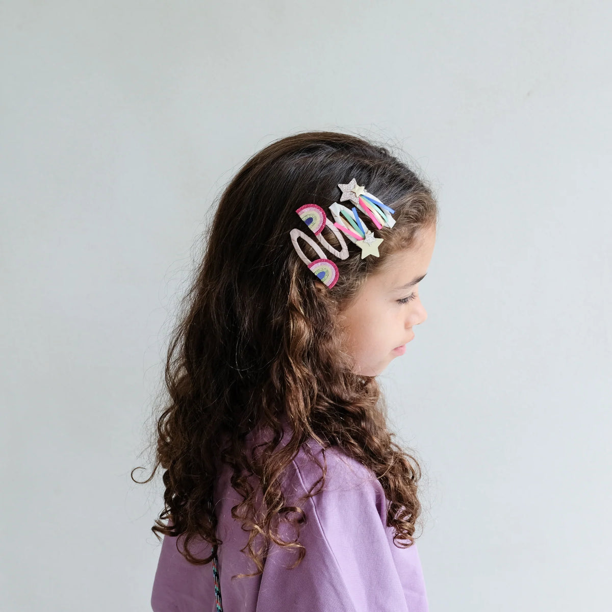 Child with a colorful hair clip on a plain background