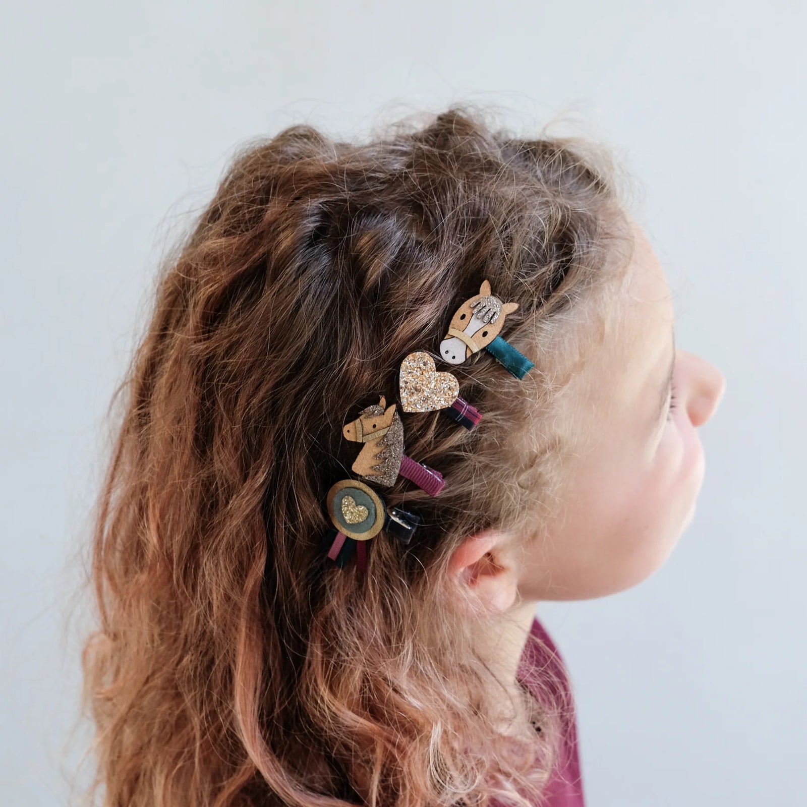 Child with decorated hair clips on a plain background