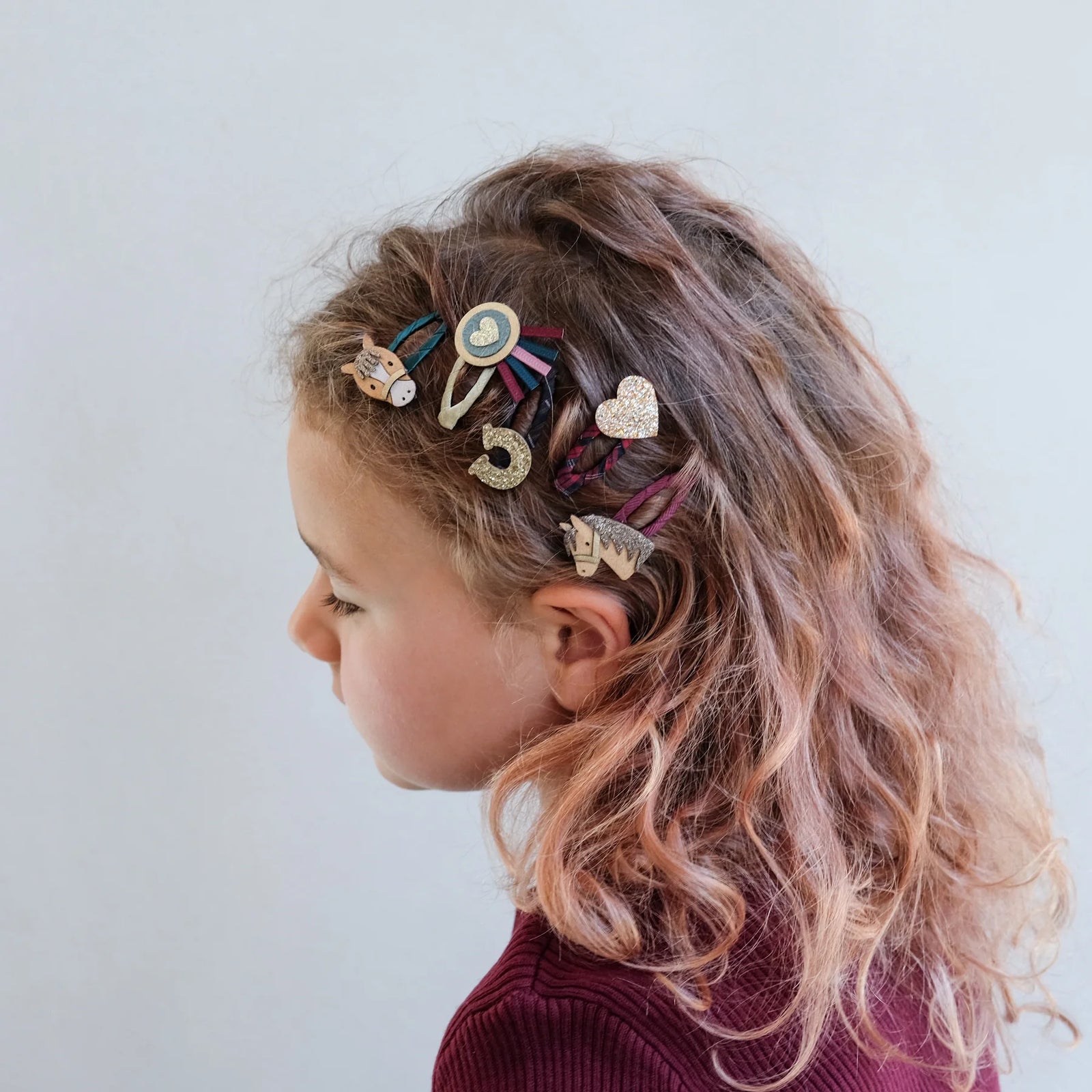 Child with styled hair featuring colorful hair clips on a plain background