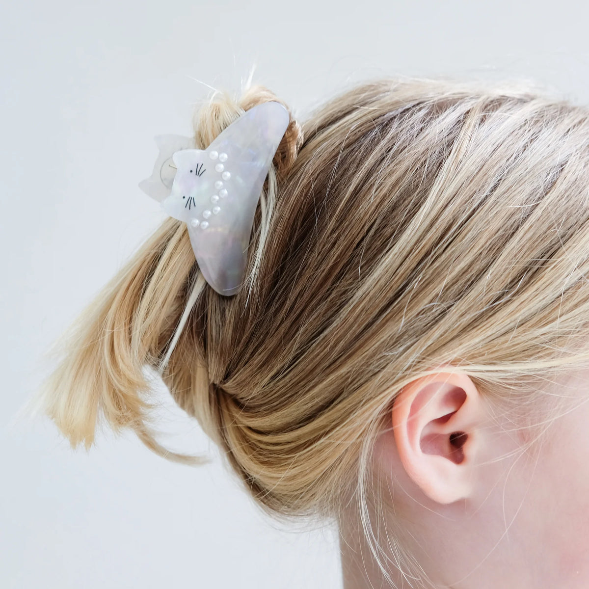 Hair clip with cat design on a child&#39;s hair against a white background