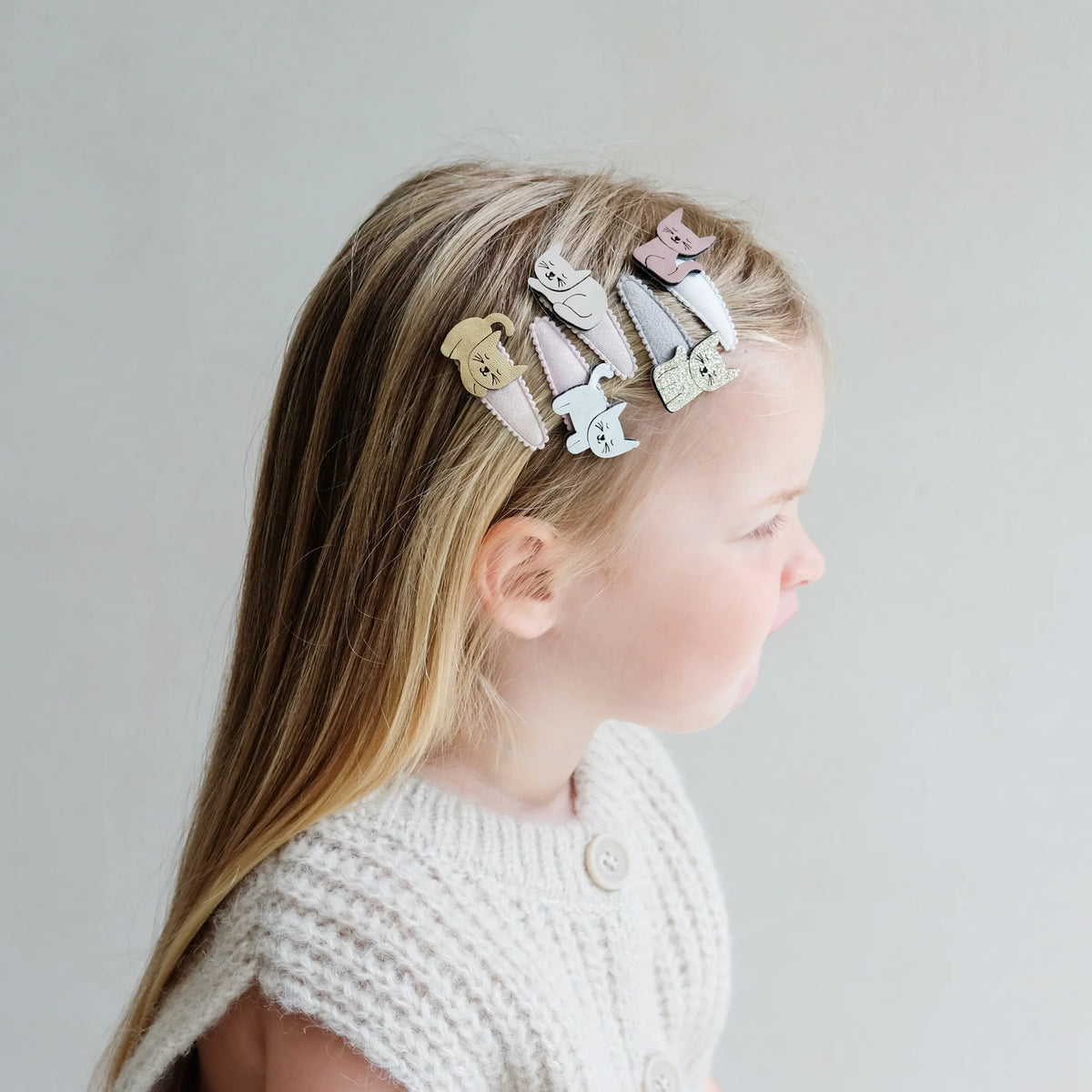 Young girl with decorative hair clips in her hair against a plain background