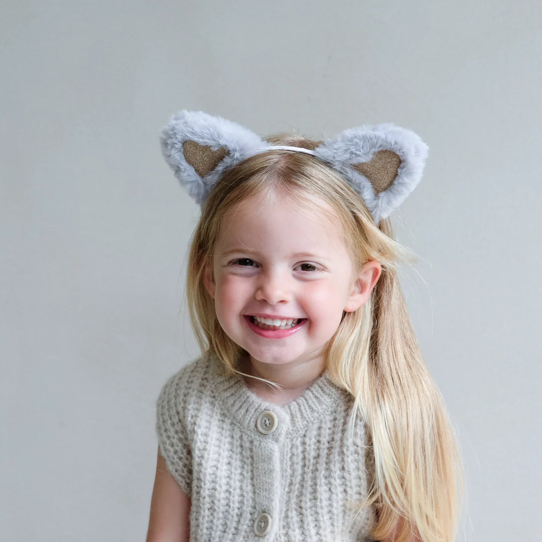 Child wearing fluffy cat ears with a plain background