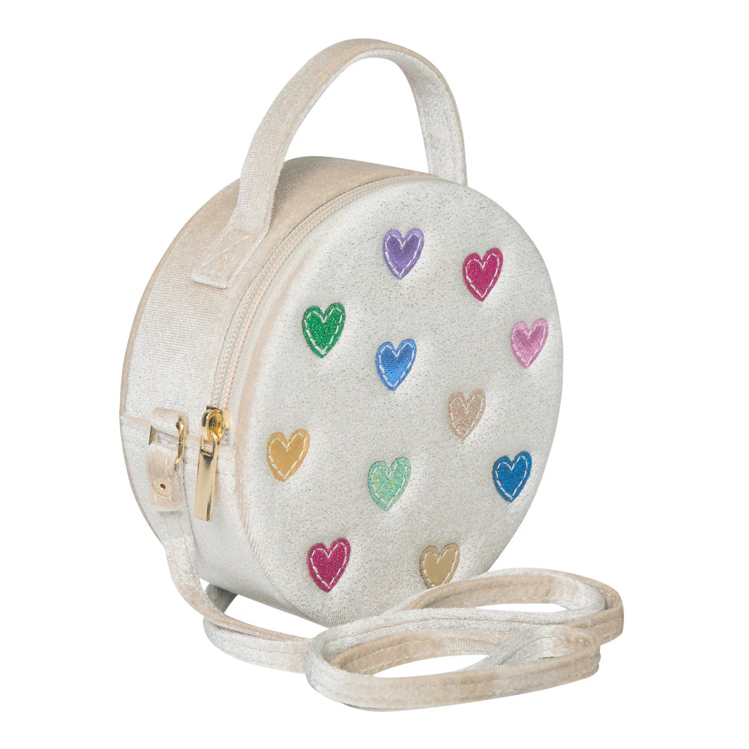 Young girl holding a round bag with heart designs against a plain background