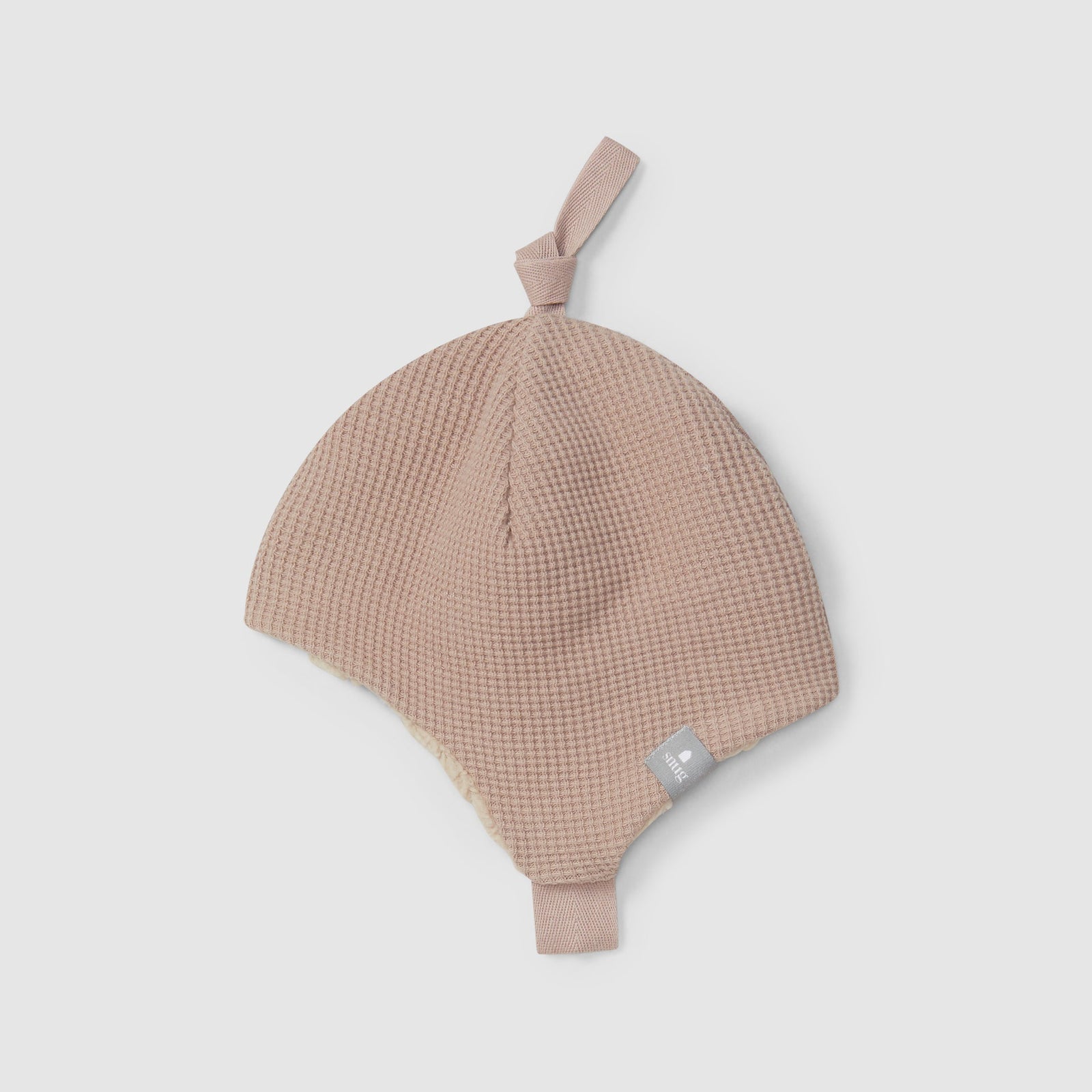 Pink baby hat with a strap on a light gray background