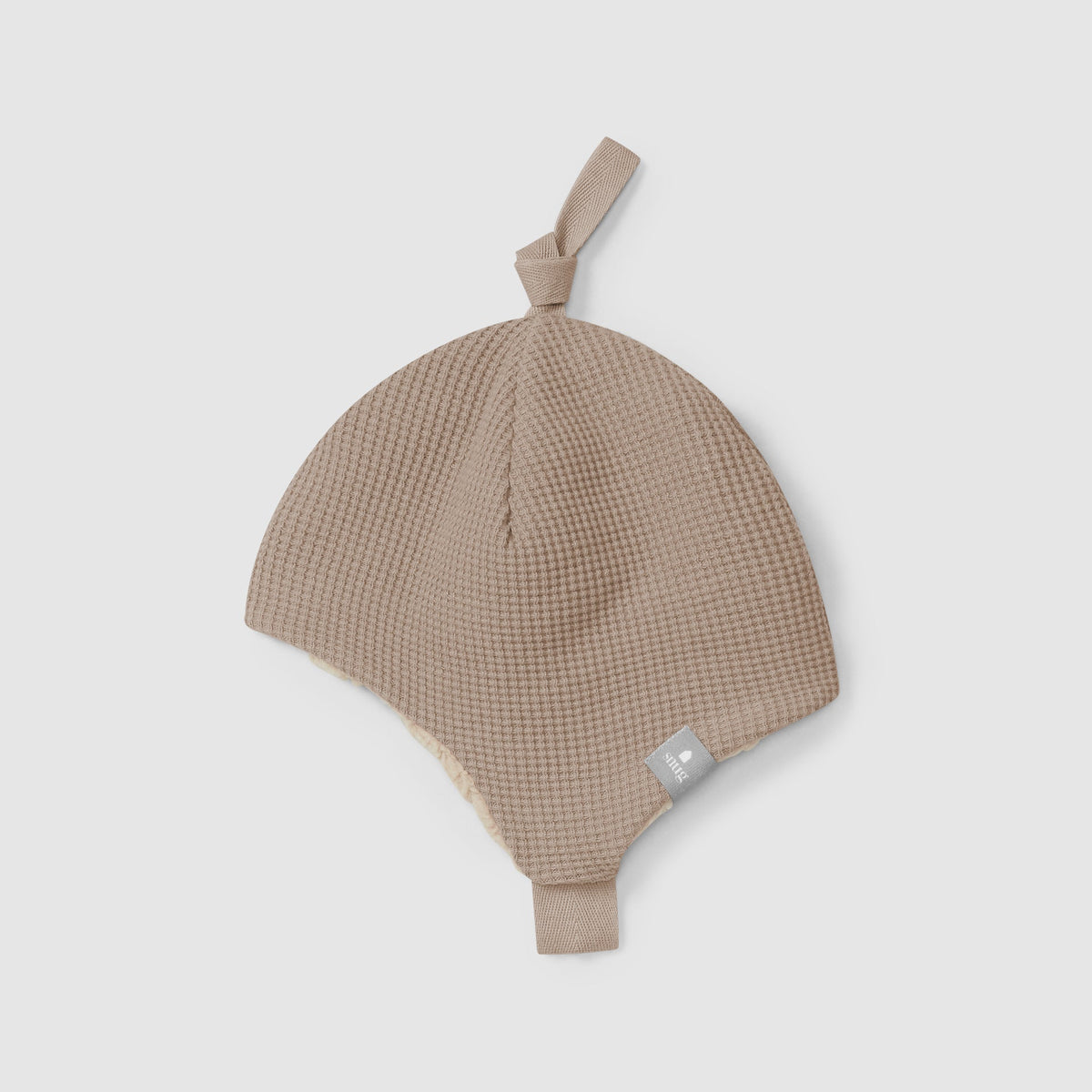 Beige baby hat with a strap on a light gray background
