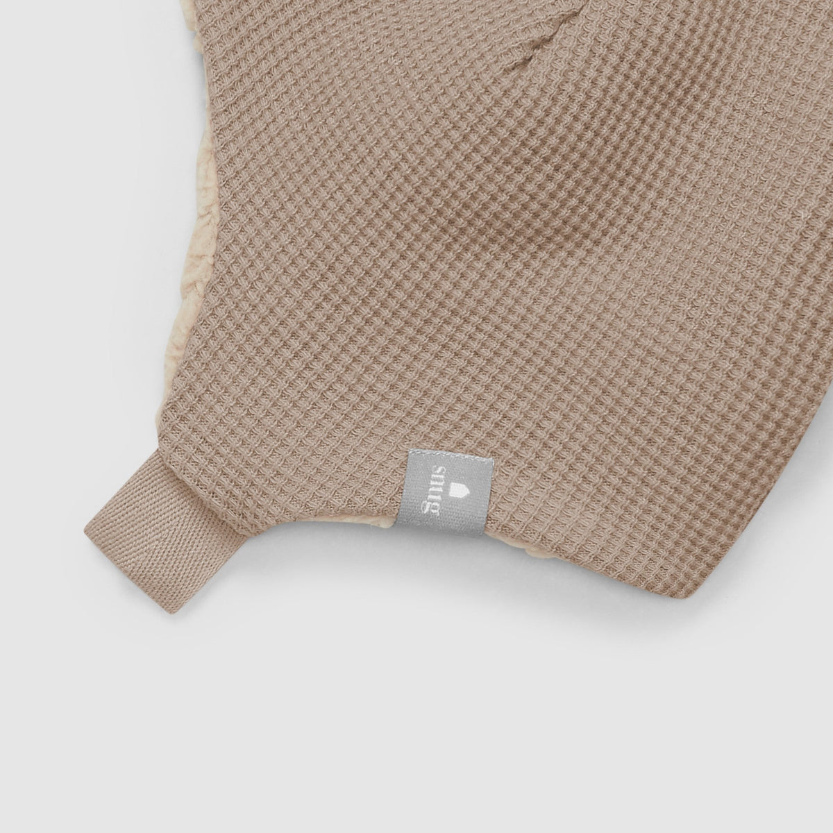 Beige textured towel with a brand tag on a white background