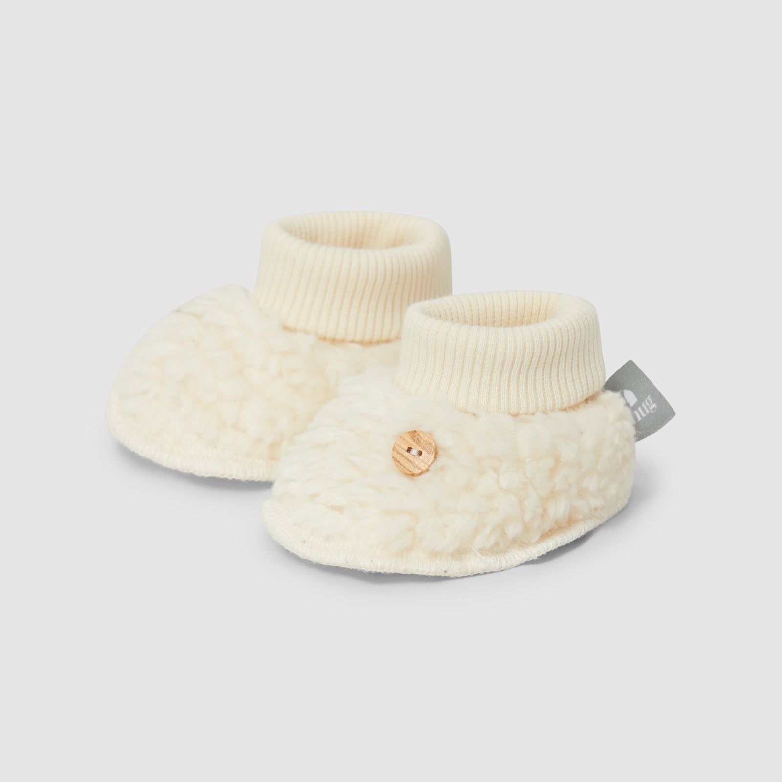 Pair of cream-colored baby booties on a white background