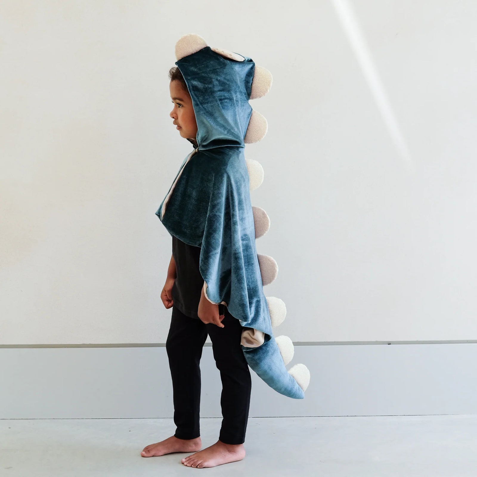 Child wearing a blue dinosaur costume with a white background