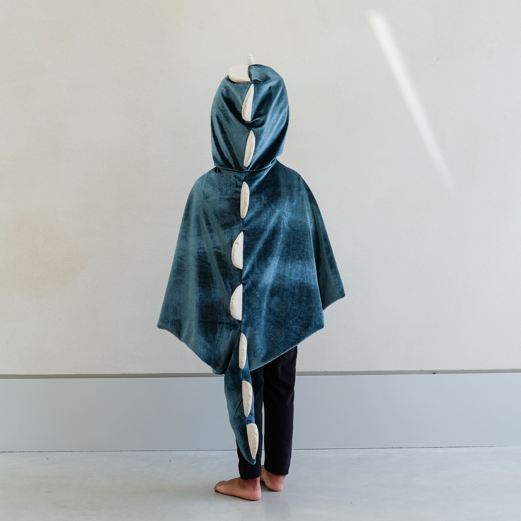 Child wearing a blue dinosaur costume with a white background