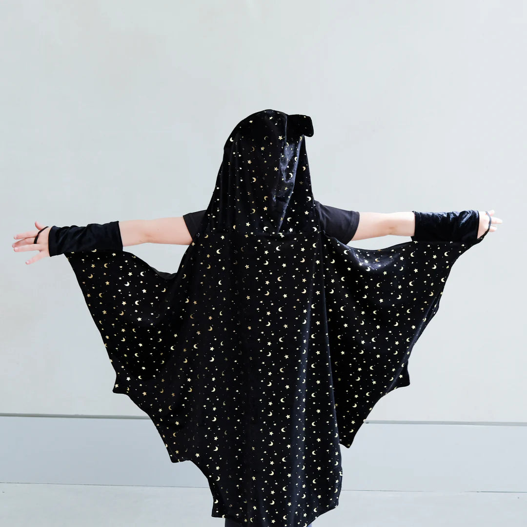 Child wearing a black bat costume with a hood against a light gray background