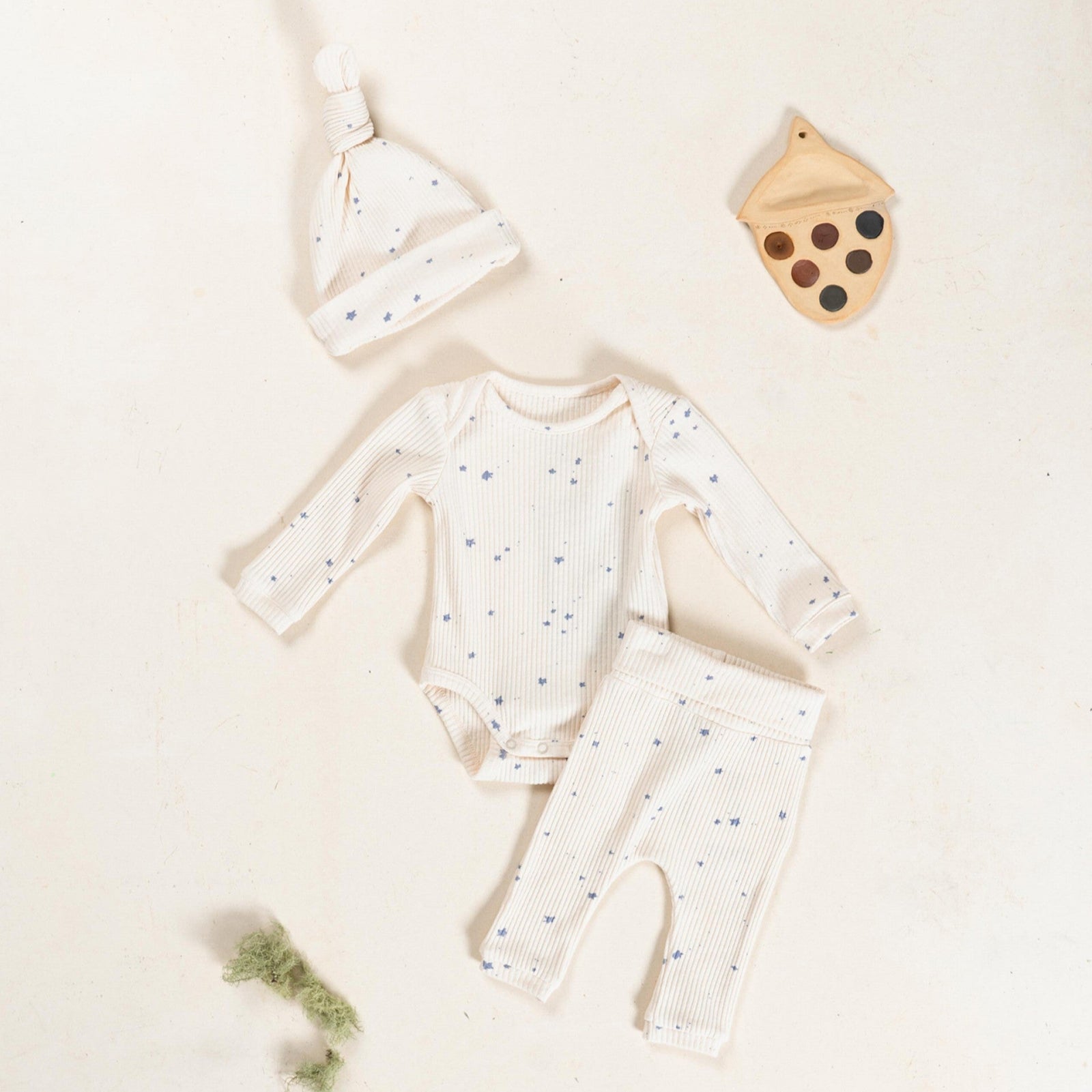 Baby outfit with onesie, hat, and pant on a light background