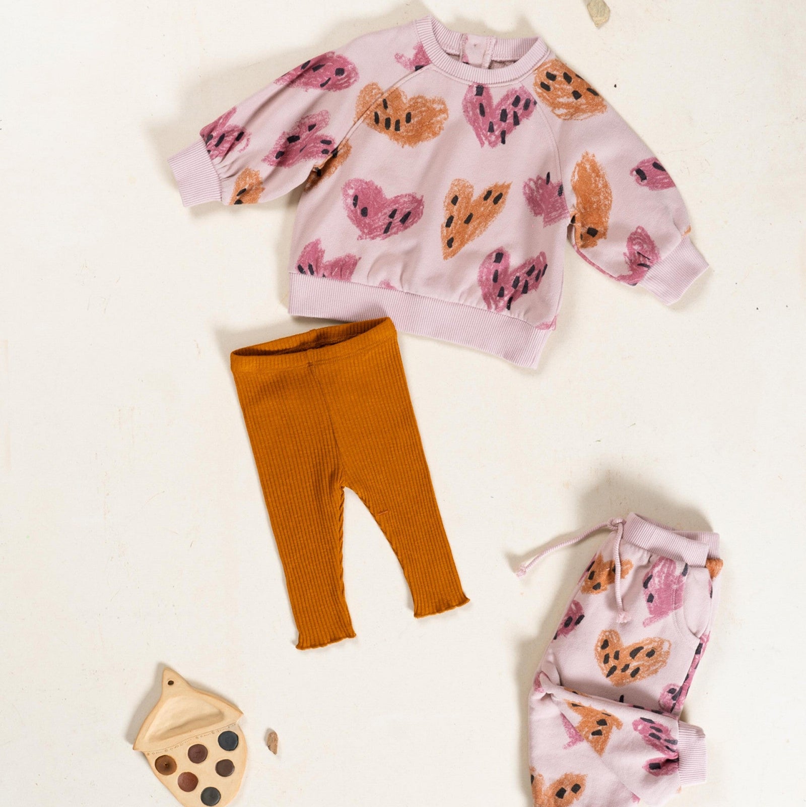 Children's outfit with pink sweater and orange pants on a white background