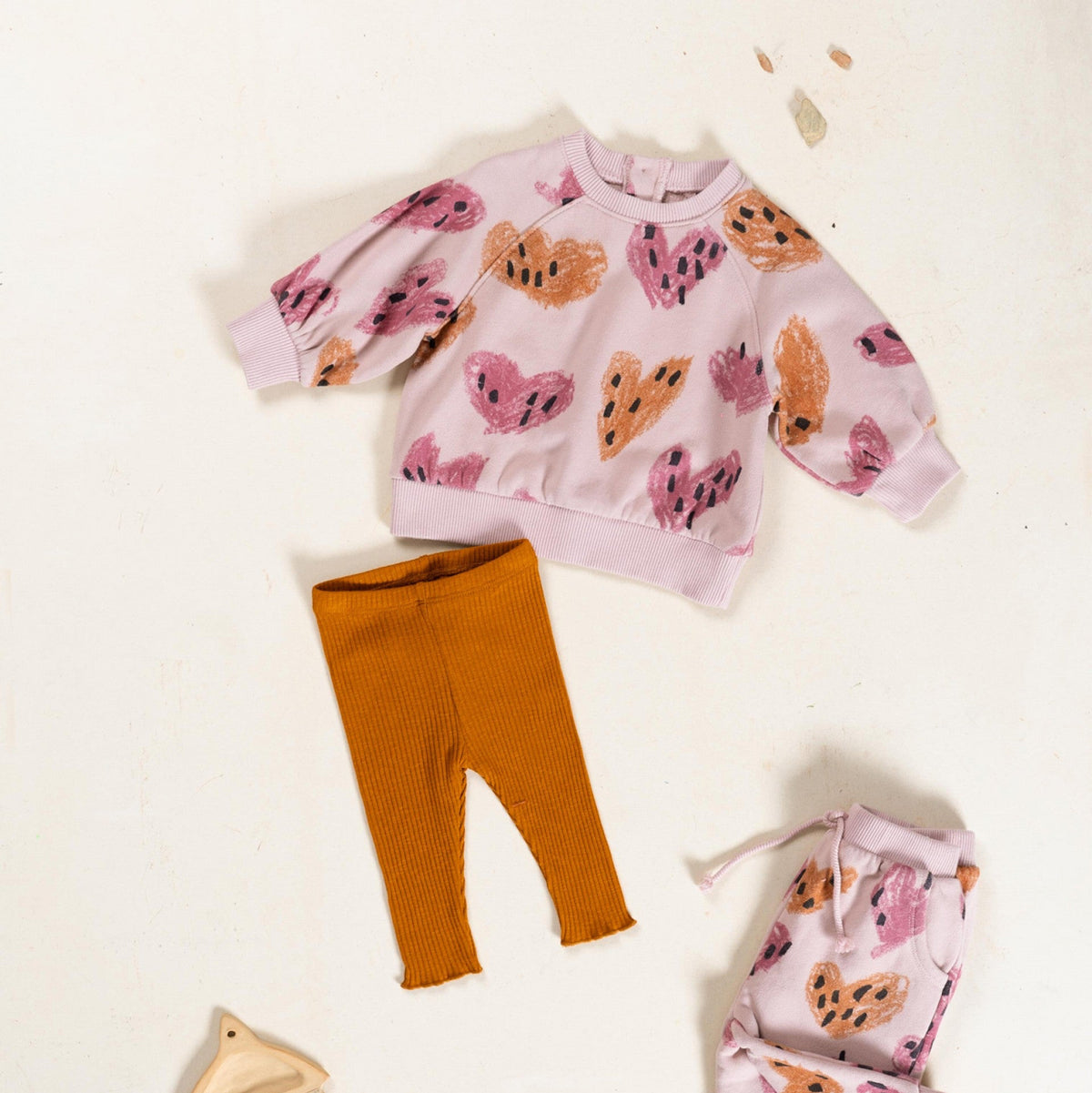 Children&#39;s outfit with pink sweater and orange pants on a white background