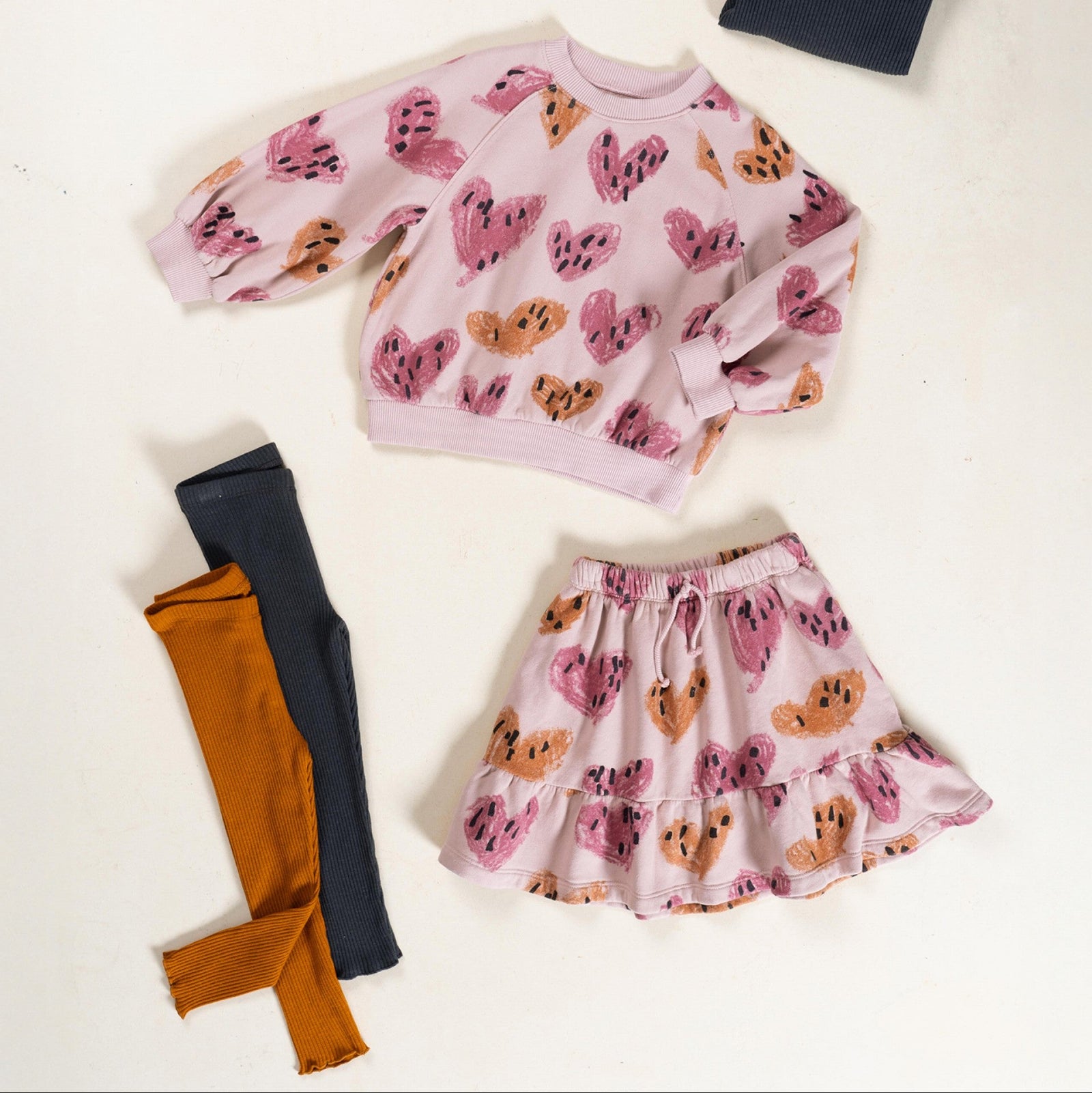 Children's outfit with pink sweater and orange pants on a white background