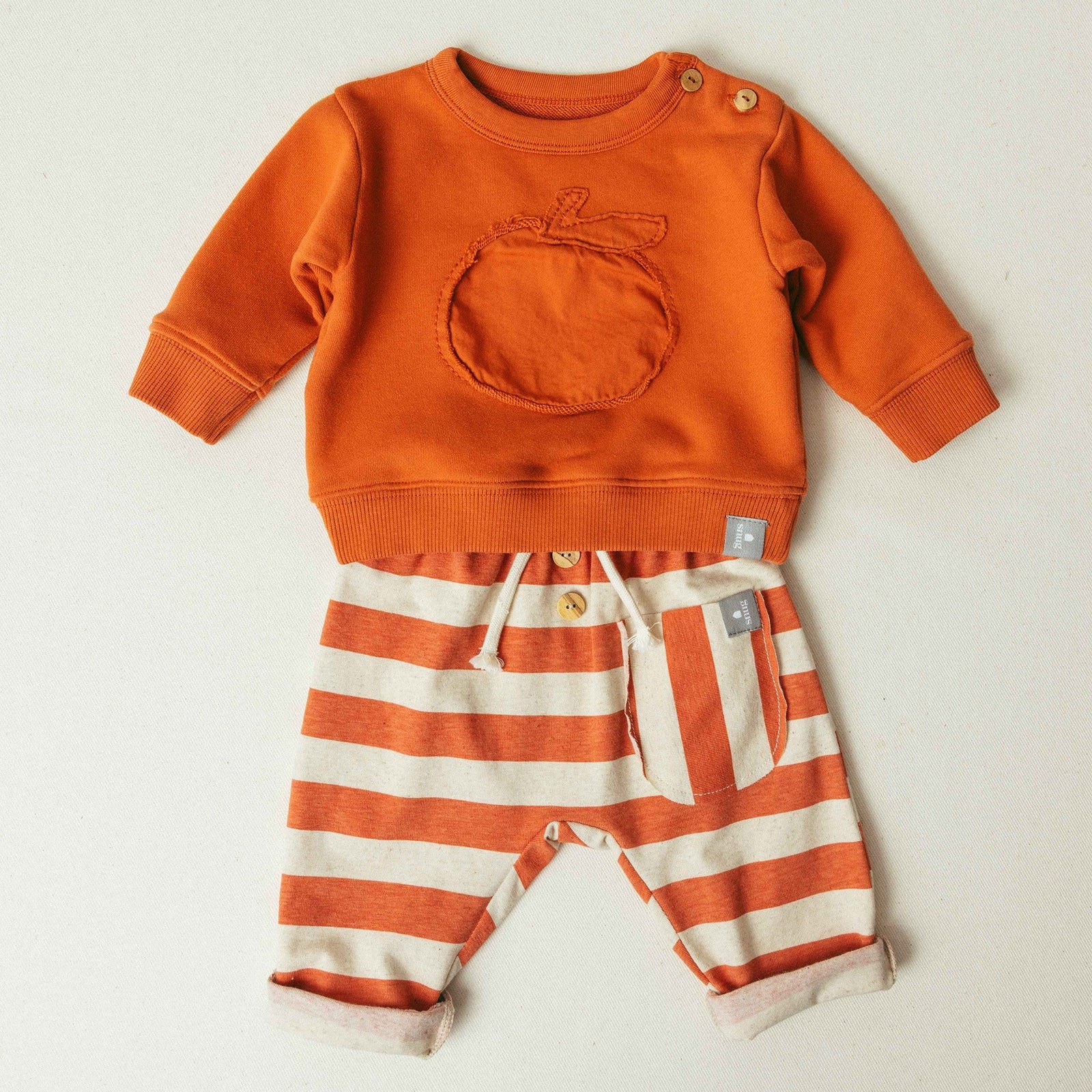 Striped baby pants with buttons on a light gray background