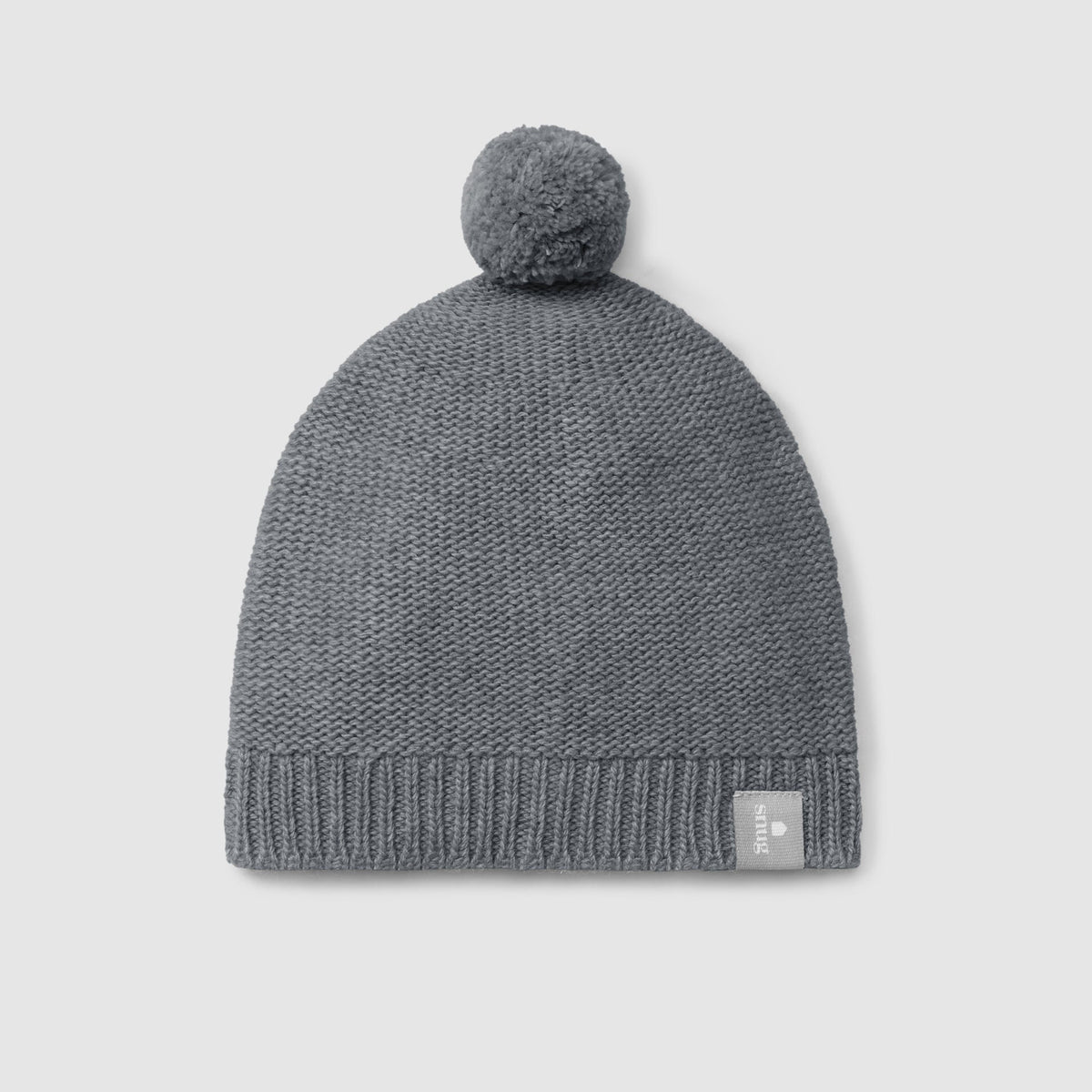 A dark gray knit beanie hat with a matching pom-pom on top and a small square brand tag on the lower right edge, shown against a light gray background.