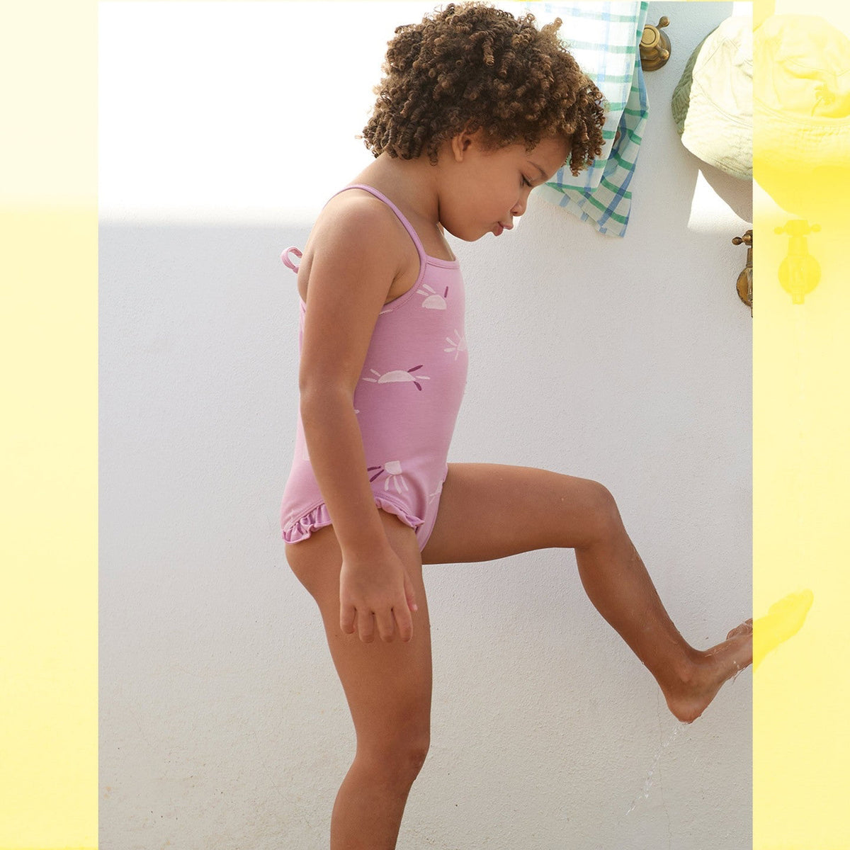 Child wearing a pink swimsuit standing on a white background