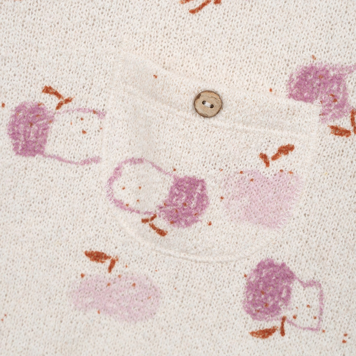 Close-up of a textured fabric with pink and purple patterns and a button.