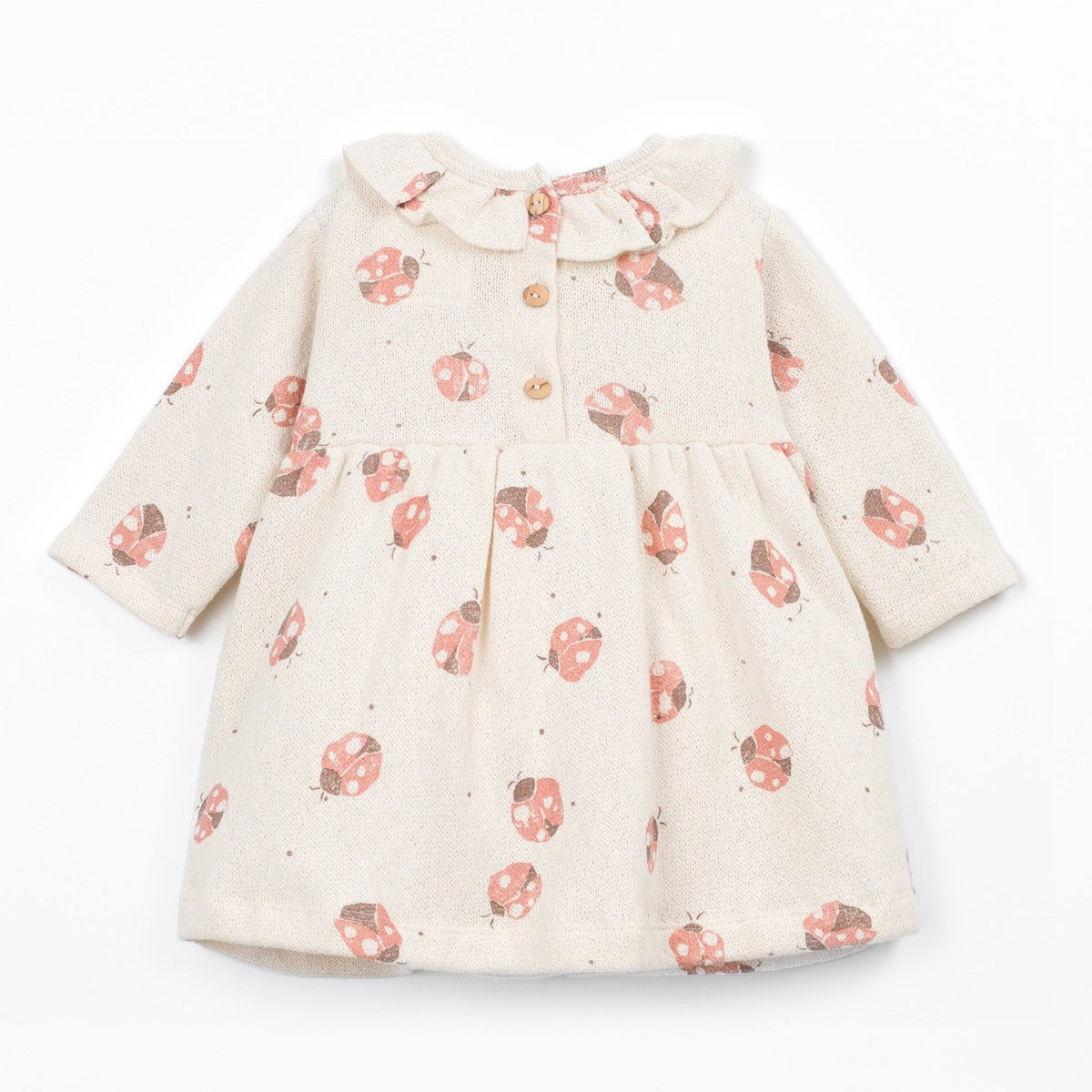 A baby girl's long-sleeve dress in cream linen fabric with a red and pink ladybug print, featuring a ruffled collar and three wooden buttons.