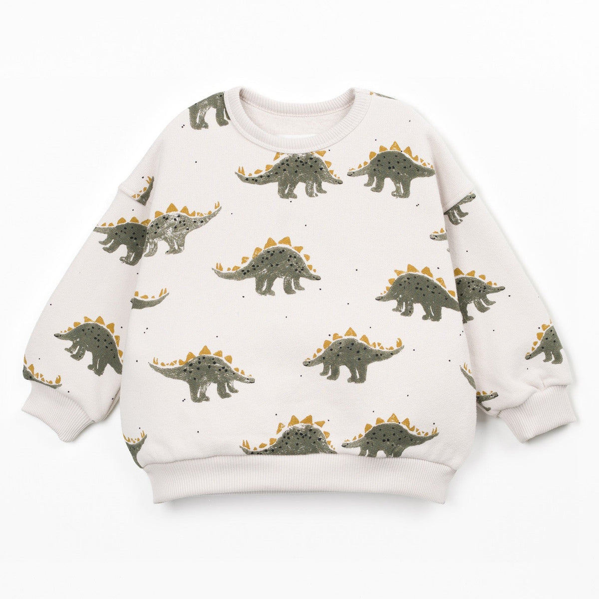 A long-sleeve crewneck sweatshirt for kids, featuring an all-over print of green and brown Stegosaurus dinosaurs with orange-yellow spikes on a warm off-white background.
