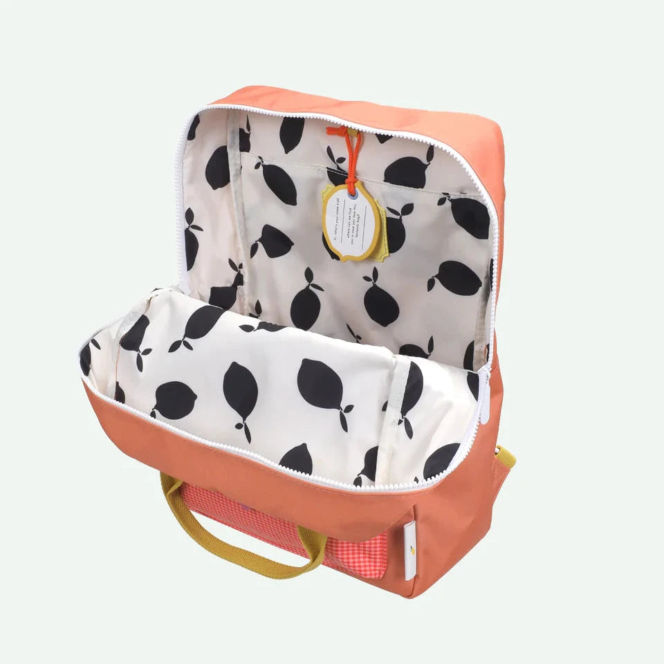 Backpack with open lid showing black lemon pattern interior on a light gray background