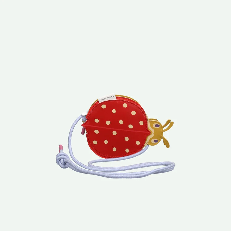 Ladybird-shaped pouch with a strap on a white background