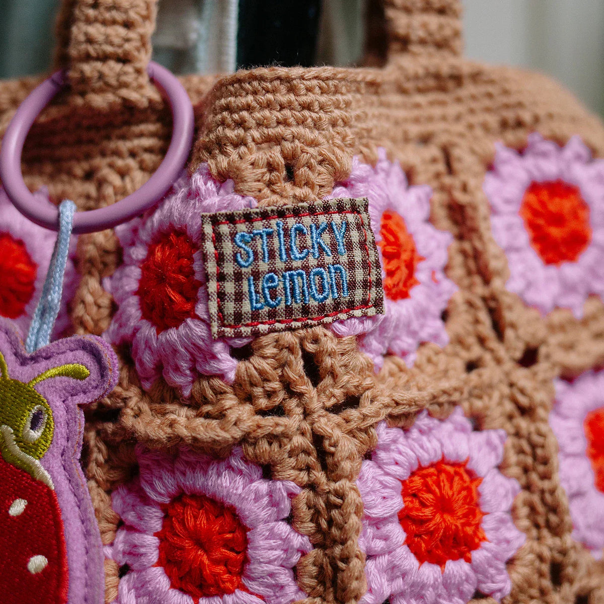 Crocheted bag with floral patterns and 'Sticky Lemon' label