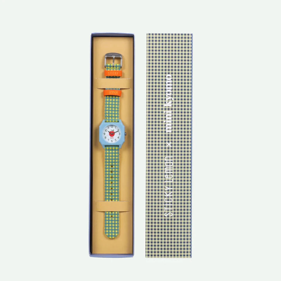 Wristwatch with green strap and blue face in packaging on a white background